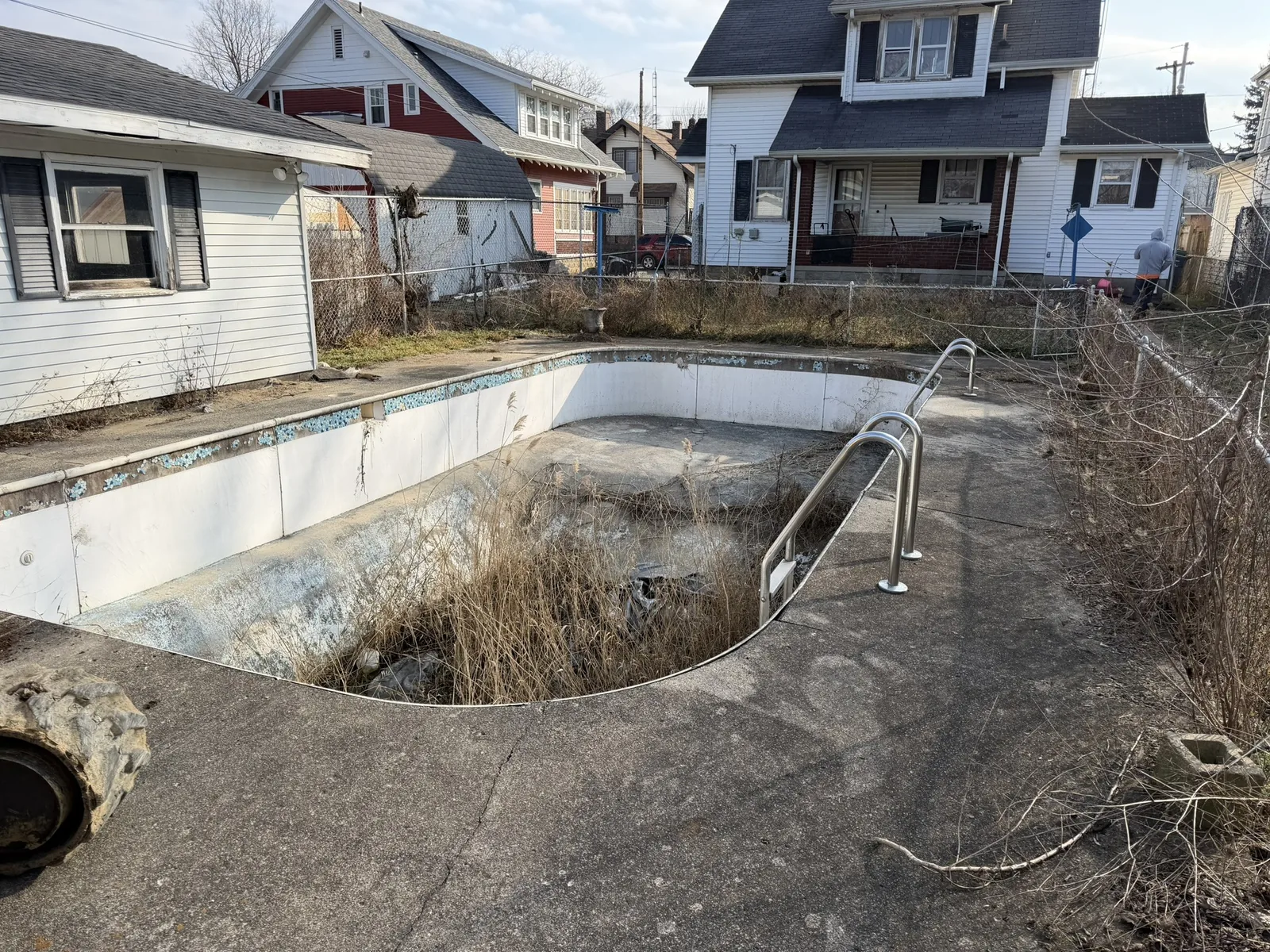 An empty in-ground residential pool before removal work begins